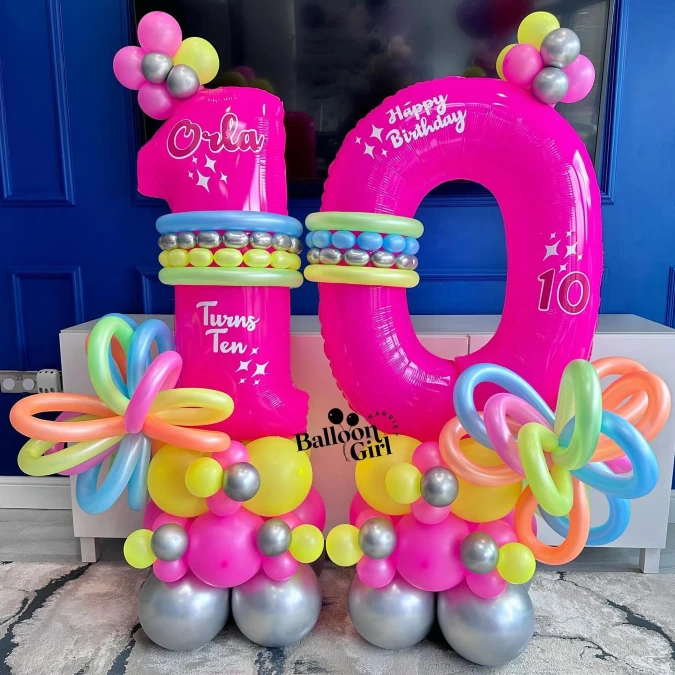 Large pink foil birthday numbers surrounded by bright twisted balloons